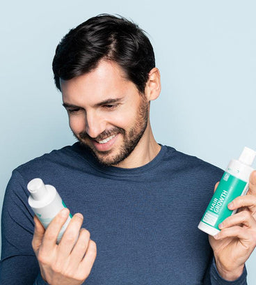 Man holding Neofollics hair growth stimulating shampoo