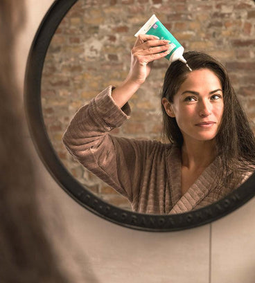 Woman applying neofollics scalp therapy nourishing mask