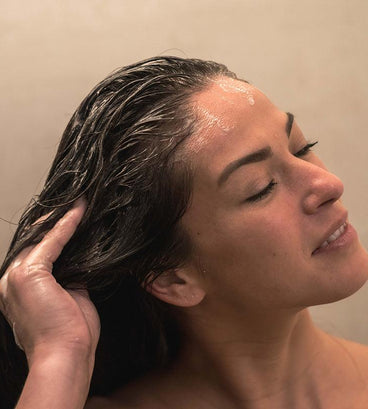 Woman showering with neofollics scalp exfoliating shampoo