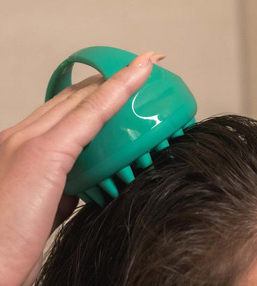 Woman massaging scalp with Neofollics scalp massaging shampoo brush