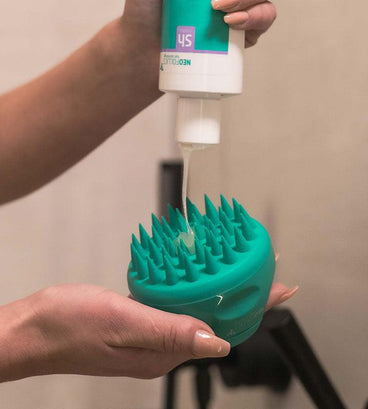 Woman applying scalp shampoo on Neofollics scalp massaging shampoo brush