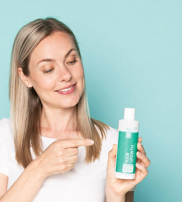 Woman pointing at Neofollics hair growth stimulating shampoo