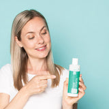 Woman holding Neofollics hair growth stimulating shampoo
