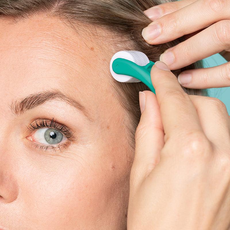 Woman rolling dermaroller on scalp