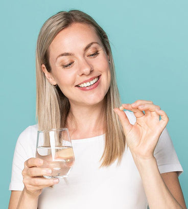 Woman holding Neofollics hair growth supporting tablets and a glass of water