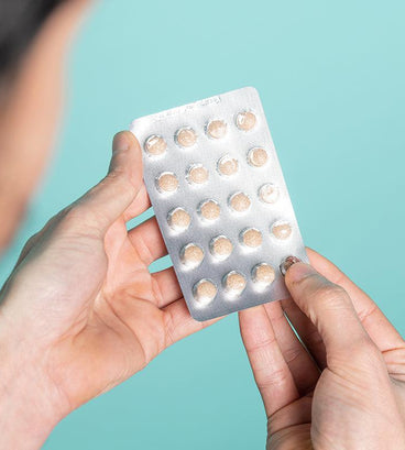 Man holding neofollics hair growth supporting tablets