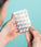 Man holding neofollics hair growth supporting tablets