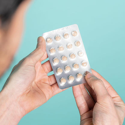Man holding a case of Neofollics hair growth supporting tablets