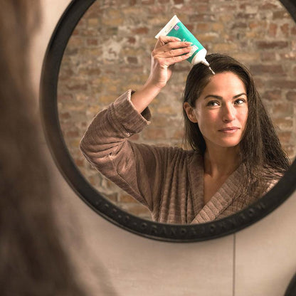Woman applying neofollics scalp therapy nourishing mask
